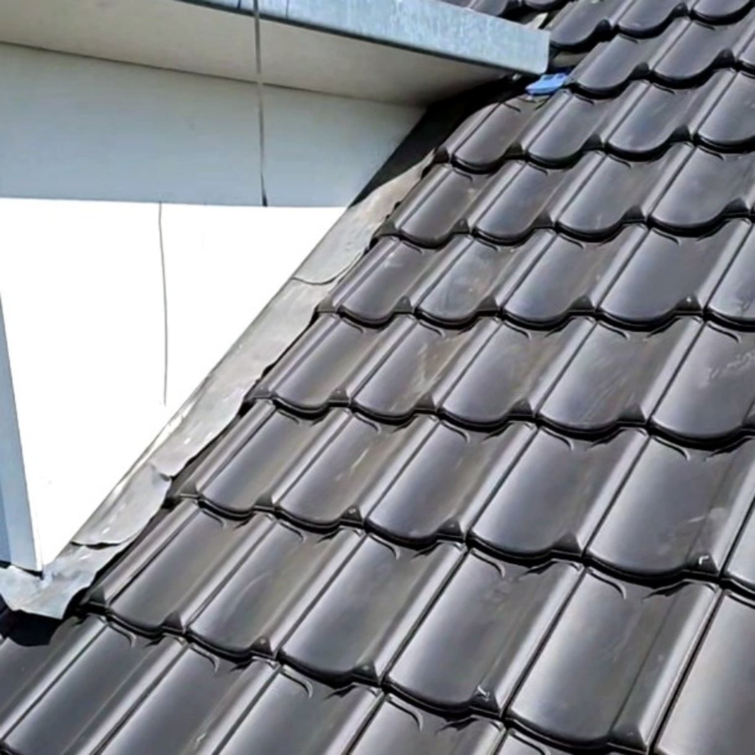Dakpannen met een loden aansluiting tegen de zijwand van een dakkapel