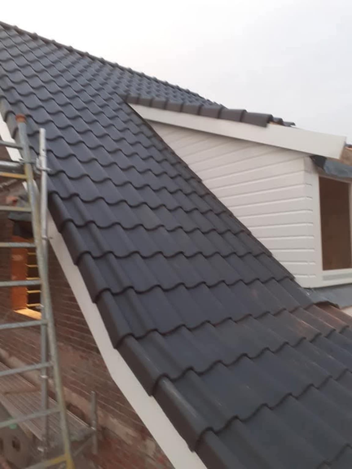 Afgewerkt pannendak met nieuwe dakpannen en een witte dakkapel